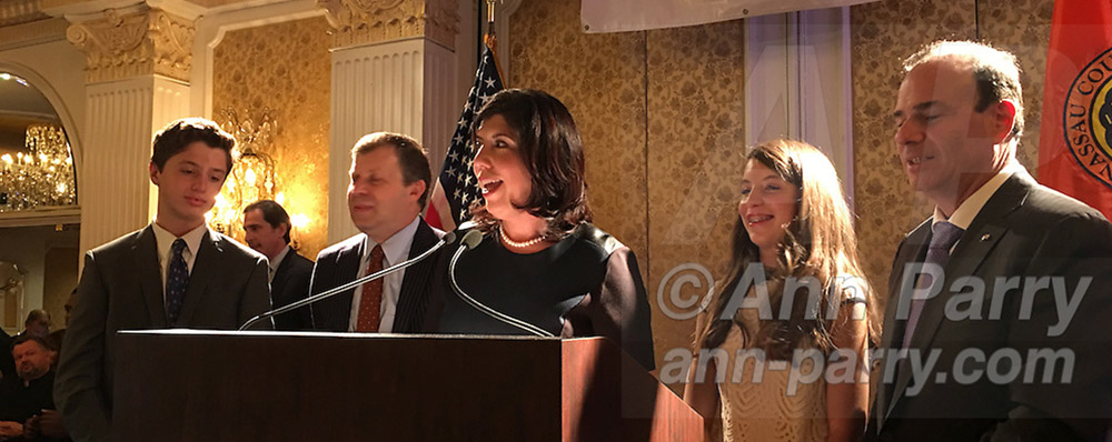 Garden City, New York, USA. Nov. 3, 2015. At center, Democrat MADELINE SINGAS claims victory over Republican Kate Murray in race for Nassau County District Attorney. Singas's family - including (left of her) her husband Theo Apostolou, (right of her) daughter, and son, and Jay Jacobs (far right) Chairman of Nassau County Democratic Committee) joined her on stage at Nassau County Democrats Election Night Party at Garden City Hotel.