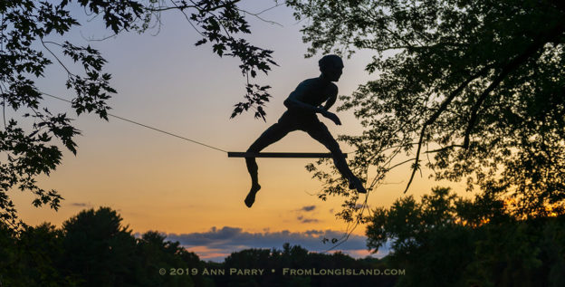 Old Westbury, NY, U.S., Sept. 1, 2019. "Athlete 1 - Over the Hurdle" seen silhouetted by sky at upper right, is one of 33 outdoor sculptures by Jerzy Kedziora (Jotka), b. 1947 in Poland, and his Balance in Nature art is on view at historic Old Westbury Gardens in Long Island, until October 13, 2019.