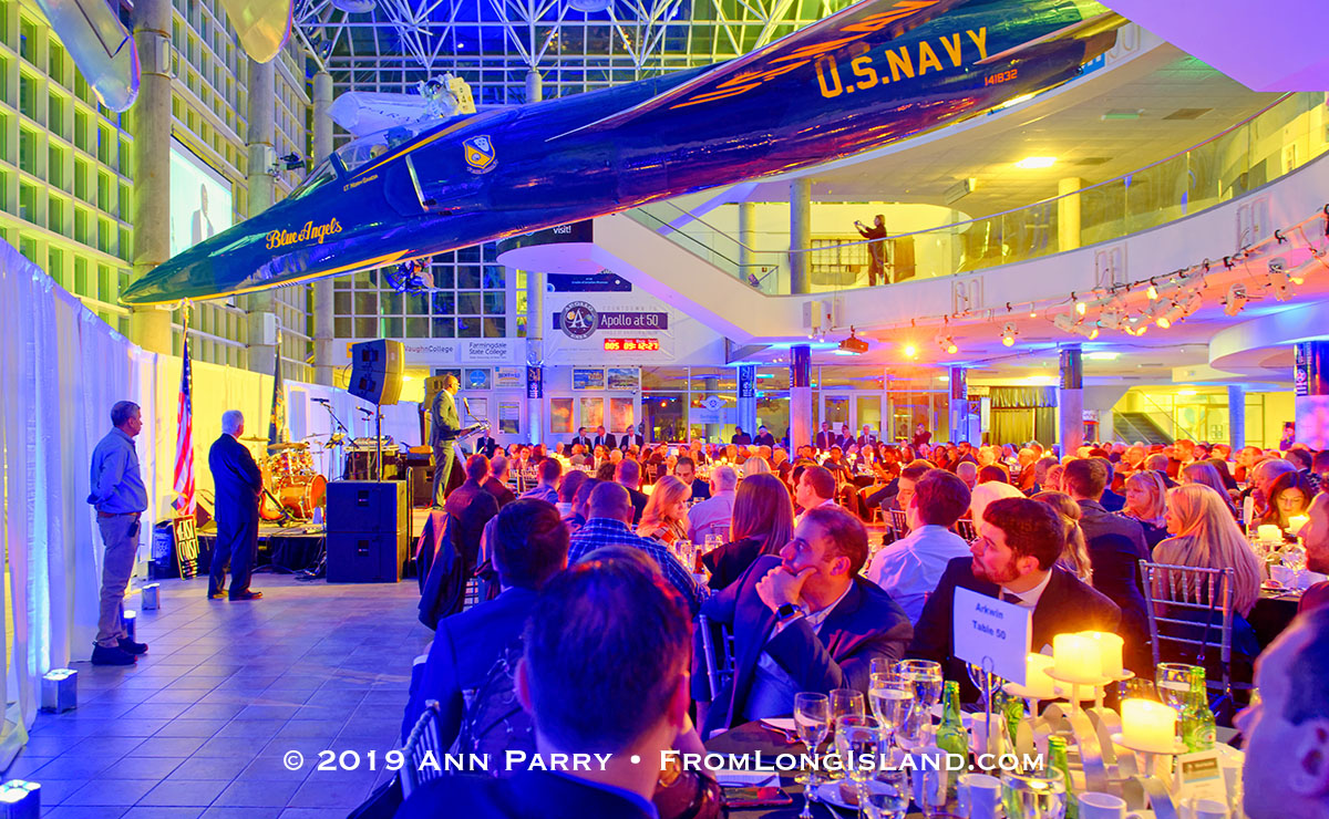 Garden City, NY, U.S., Nov. 14, 2019. HUNTLEY LAWRENCE, the Aviation Leadership Award honoree, speaks at podium under U.S. Navy Grumman F11 jet suspended from atrium ceiling, as guests look on during 7th Annual Cradle of Aviation Museum Air and Space Gala.