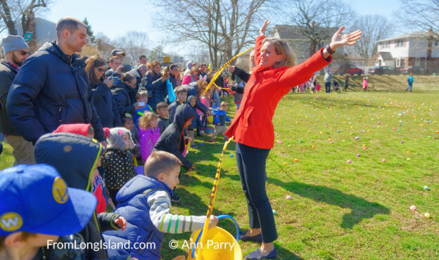 North Merrick, New York, USA. March 31, 2018. Nassau County Executive LAURA CURRAN flings her arms up high after cutting the yellow tape to start the Egg Hunt at the Annual Eggstravaganza, held at Fraser Park and hosted by North and Central Merrick Civic Association (NCMCA) and Merrick's American Legion Auxiliary Unit 1282. Young children rush to collect eggs in their Easter baskets. (© 2018 Ann Parry, Ann-Parry.com)