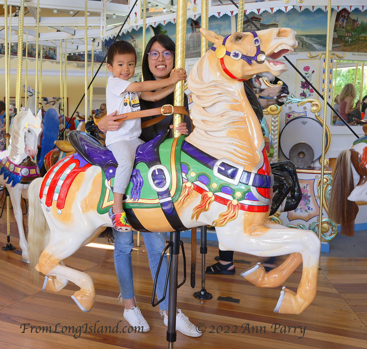Garden City, New York, U.S. August 16, 2022. AARON, 2, of East Meadow, rides on a horse, with his mother holding him, when historic Nunley's Carousel officially reopens after Covid-19 pandemic forced it to close in 2020. (© 2022 Ann Parry, annparry.com)