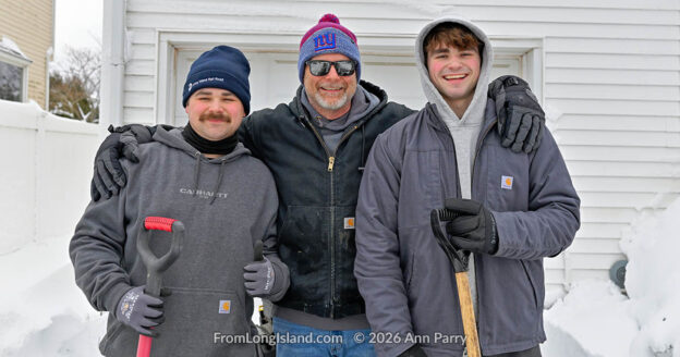 Merrick, New York, U.S., February 23, 2026. A father and his two sons shovel their neighbor's home, in the south shore of Nassau County, after a northeast snowstorm dropped about two feet of snow across Long Island.